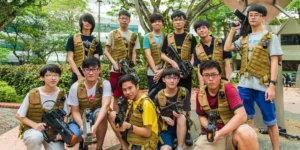 Group of young individuals in tactical vests holding toy guns outdoors.